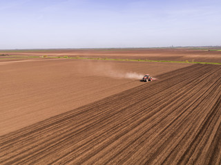 Aerial shot of a tractor cultivating field at spring