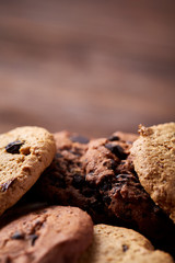Side view of chocolate chip cookies on a wooden plate over rustic background, selective focus