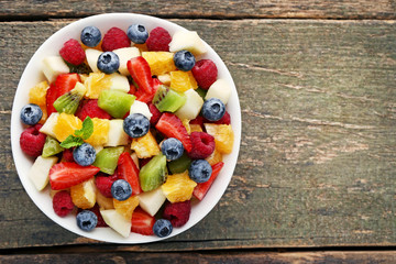 Fresh fruit salad in bowl on grey wooden table