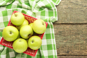 Ripe green apples in basket on wooden table
