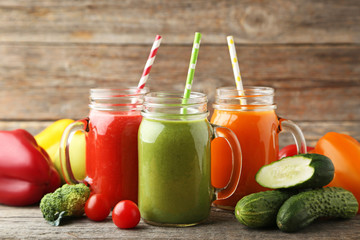 Vegetables smoothie in jars on wooden table