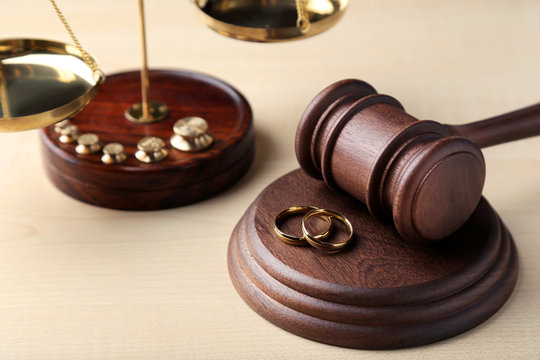 Judge gavel with wedding rings on wooden table