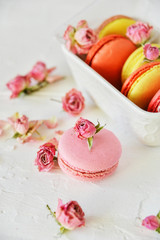 Fototapeta na wymiar Delicate Fresh Colorful French Macaroons In Pastel Colors With Flowers Roses On A Light Textile Background