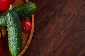 Wooden plate with vegetables for a vegetarian salad on rustic wooden background, close-up, selective focus