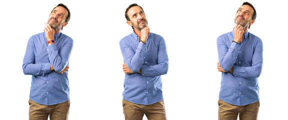 Middle age handsome man thinking and looking up expressing doubt and wonder over white background