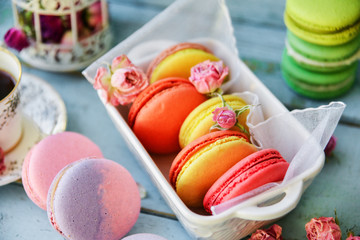 Dessert With Coffee: A Delicate Fresh French Macaroons In Pastel Colors Gift Box Flowers Roses On Light Blue Wooden Background