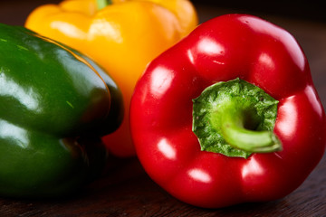 Combination of fresh organic green, yellow and red pepper on rustic wooden background.