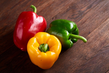 Combination of fresh organic green, yellow and red pepper on rustic wooden background.