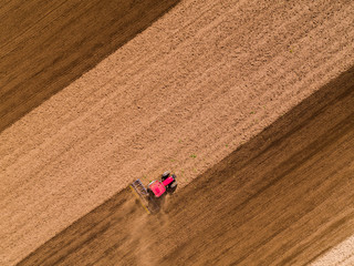 Aerial shot of a tractor cultivating field at spring