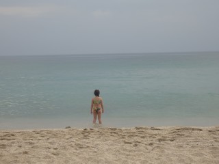 Little girl is playing on the beach alone