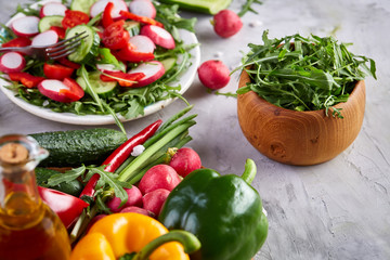 Creative fresh vegetable salad with ruccola, cucumber, tomatoes and raddish on white plate, selective focus
