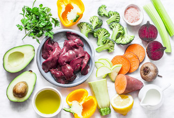 Ingredients for lunch - chicken liver, sweet potatoes, broccoli cabbage, bell peppers, beets, beans, spices, olive oil, zucchini, avocado, celery. Healthy, nutritious food set on white background