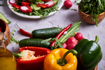 Creative fresh vegetable salad with ruccola, cucumber, tomatoes and raddish on white plate, selective focus