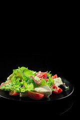 Fresh tasty salad on a glossy black background