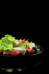 Fresh tasty salad on a glossy black background