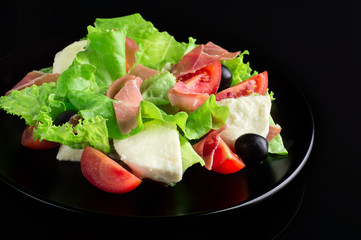Fresh tasty salad on a glossy black background