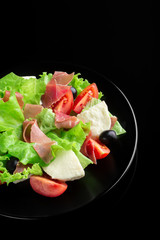 Fresh tasty salad on a glossy black background