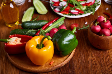 Fresh red radish in wooden bowl among plates with vegetables, herbs and spicies, top view, selective focus.