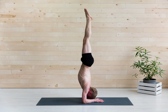 Sporty man practicing yoga.  Head stand, sirsasana exercise