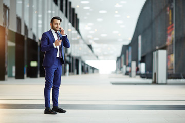 Young elegant agent in suit consulting his client during foreign travel while standing in modern airport