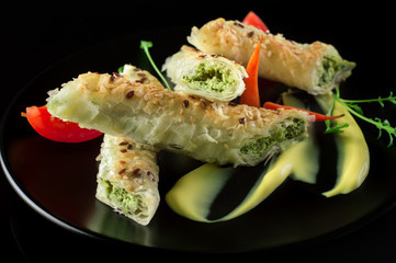 Puff pastry with spinach and cheese filling on a black plate and black background