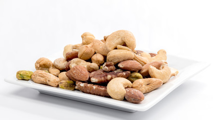 Many different kinds of fresh nuts on a white plate