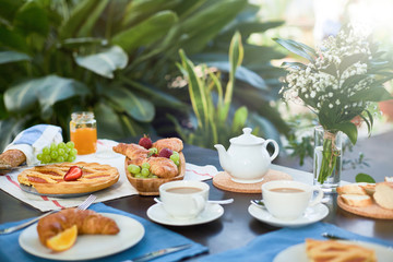 Fresh croissants, sweet homemade pie for tea and fresh fruits on served table in orangery or home-garden