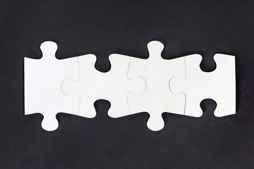 connected jigsaw puzzle pieces on black background, four in row