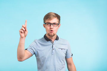 Fototapeta premium Wow, I understand it. Surprised young male raises finger as remembers something, isolated over blue background. Reaction and people