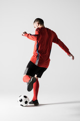 Rear view of silhouette of young football player kick ball isolated on white background