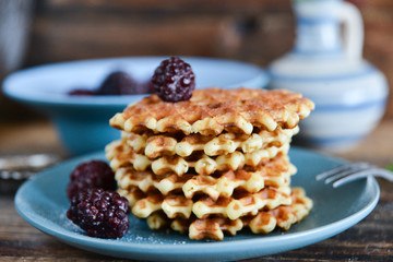 Round waffles with fresh blackberries and icing sugar on wooden background rustic