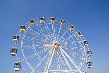 Ferris wheel over blue sky. Carousel. Cubicle. Joy.