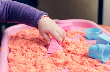 The hands of a child playing with kinetic sand
