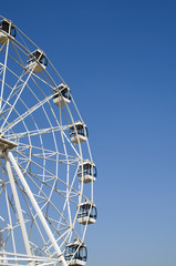 Ferris wheel over blue sky. Carousel. Cubicle. Joy.