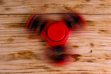 Red fidget spinner rotates on wooden desk