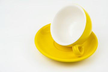 Closeup yellow ceramic coffe cup ,tilt angle on yellow plate,on white background.