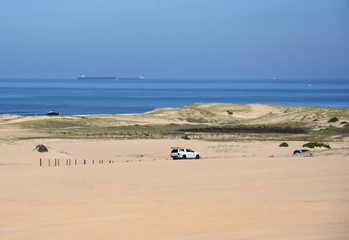 Anna bay, Australia - March 30, 2018. Horizontal landscape of the beach with cars. 4wd cars at Anna bay. Big tanker ship in the background.