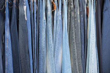 Jeans hang in a row. Pants made of woven fabric
