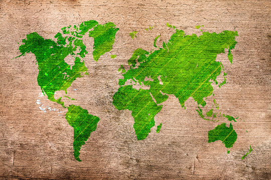 Abstract world map, which looks like green blot on wooden table. Green world map on timber board. Rural ecology theme. Eco-friendly abstract world map. © peter