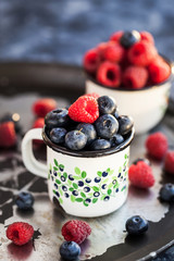 Fresh ripe blueberry and raspberry in mugs