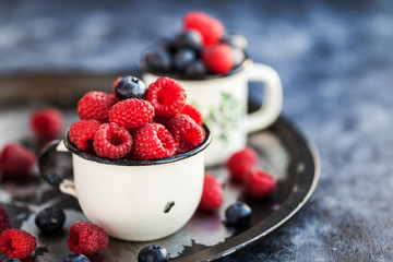 Fresh ripe blueberry and raspberry in mugs