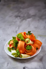 Artistically served vegetable salad with carrot, cucumber, letucce over white background, selective focus