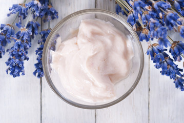 cosmetic cream and lavender flowers on white wood table background