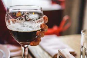 girl holding a glass half filled with dark beer.