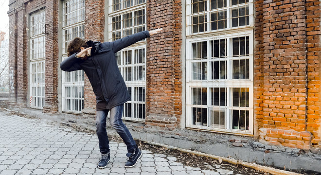 Man does a dance element dab on a street in the city evening full body