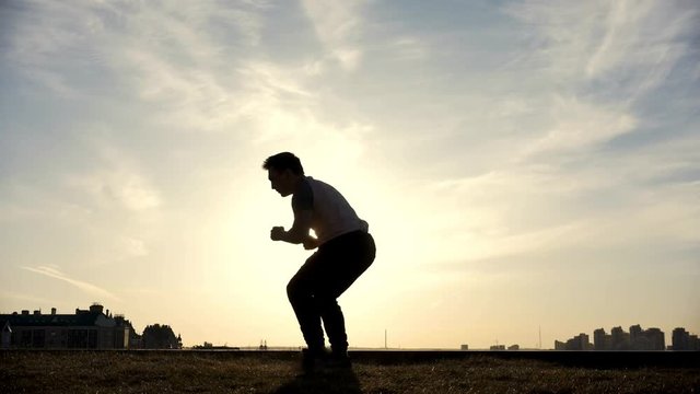 Male Parkour tricker jumper performs amazing flips, silhouette