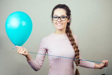 young long-haired woman with glasses is holding balloons and smiling. concept of celebration and fun. helium balloons in female hands