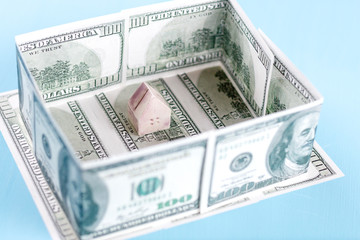 The concept of a toy house on the background of dollar bills
