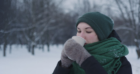 teenage girl drinking hot cocoa in park on a winter day