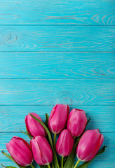 Bouquet of pink tulips on a blue wooden background. View from above.